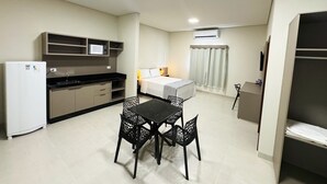 A compact living space with a kitchenette, a dining area with a table and chairs, a bed, and a wardrobe.