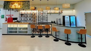 A modern bar area with a neon sign, multiple hanging lights, and bar stools.