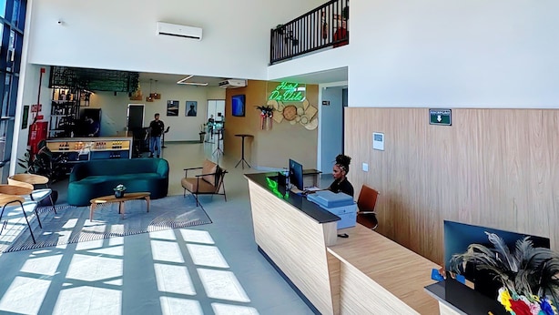 A modern reception area with a wooden reception desk, a green sofa, and a ceiling with hanging wicker lamps.