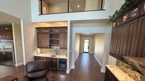 A spacious kitchen with dark wood cabinets, a stainless steel refrigerator, and a wine rack. - New Lake Paradise! 4 bdrm 3.5 ba house w/ lift, deck, grill, sauna, smart, media (Tool)