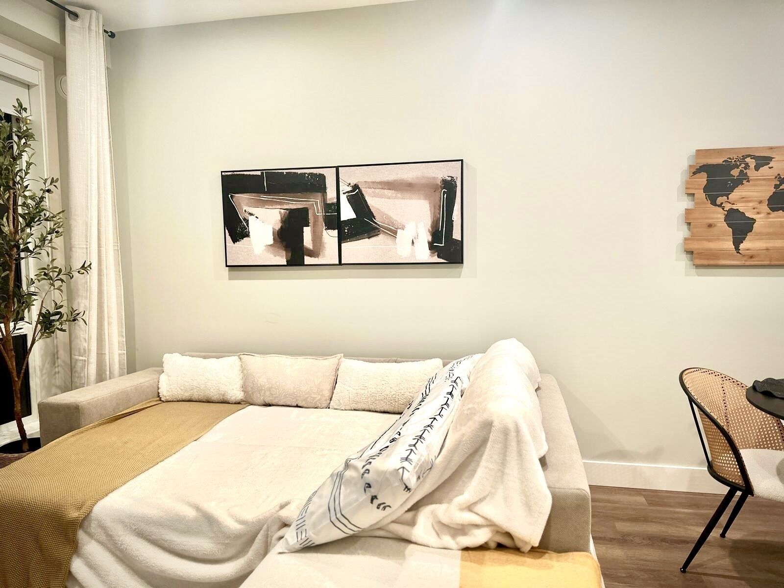 A bedroom with a bed, a plant, and artwork on the wall.