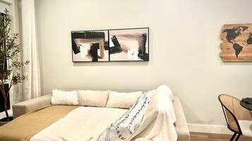 A bedroom with a bed, a plant, and artwork on the wall.