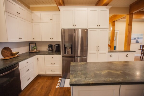 Una cocina moderna con armarios blancos, un refrigerador de acero inoxidable y una encimera de granito.