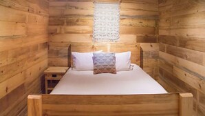 Une chambre dans un chalet en bois, avec un lit, une petite table de chevet et une décoration murale.