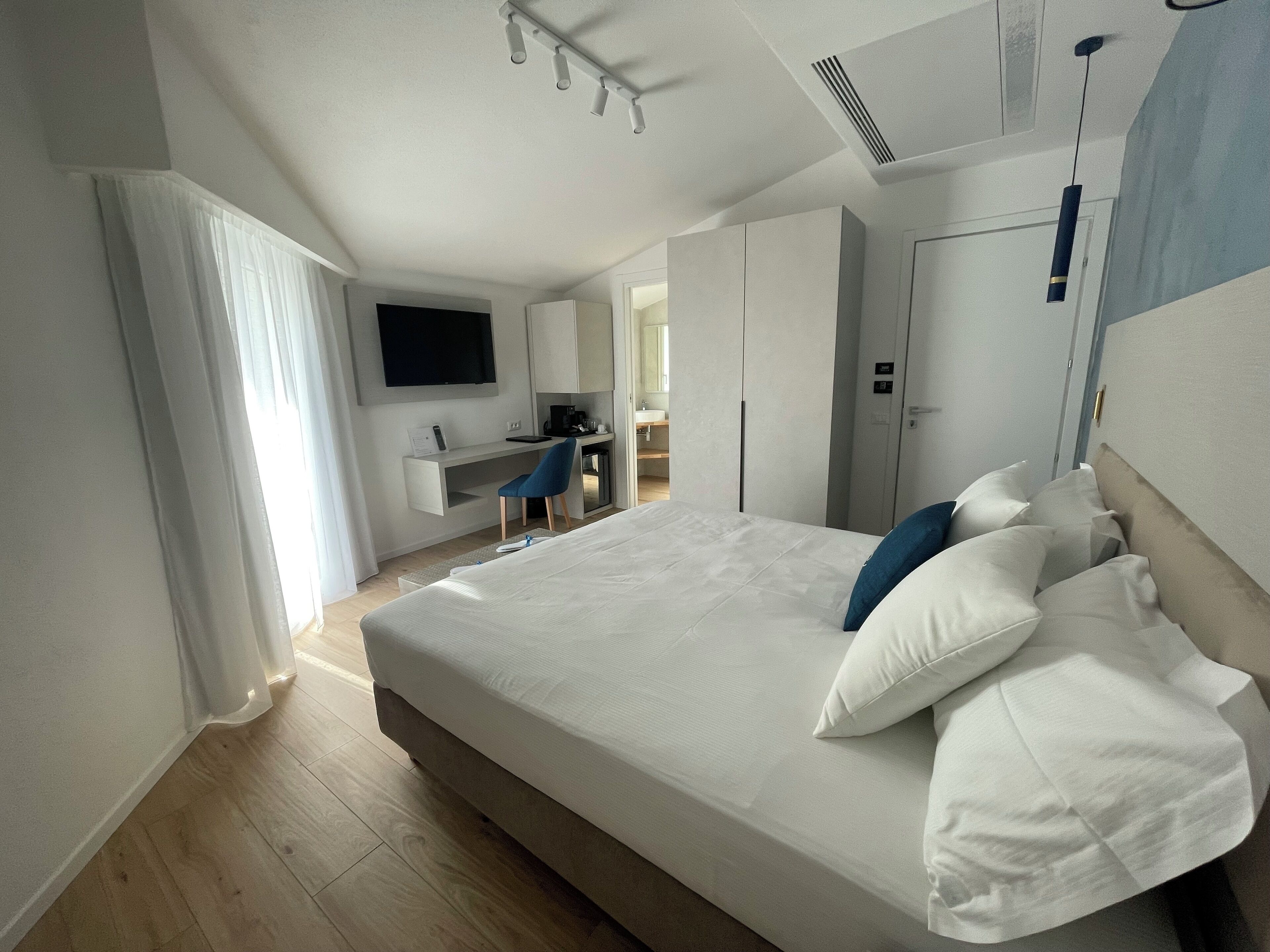 Une chambre d’hôtel moderne dotée d’un grand lit, d’un bureau avec une chaise, d’un téléviseur à écran plat fixé au mur et d’une armoire.