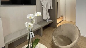 Une salle de bain moderne comprenant un meuble-lavabo, un miroir, un porte-serviettes avec des peignoirs et un banc.