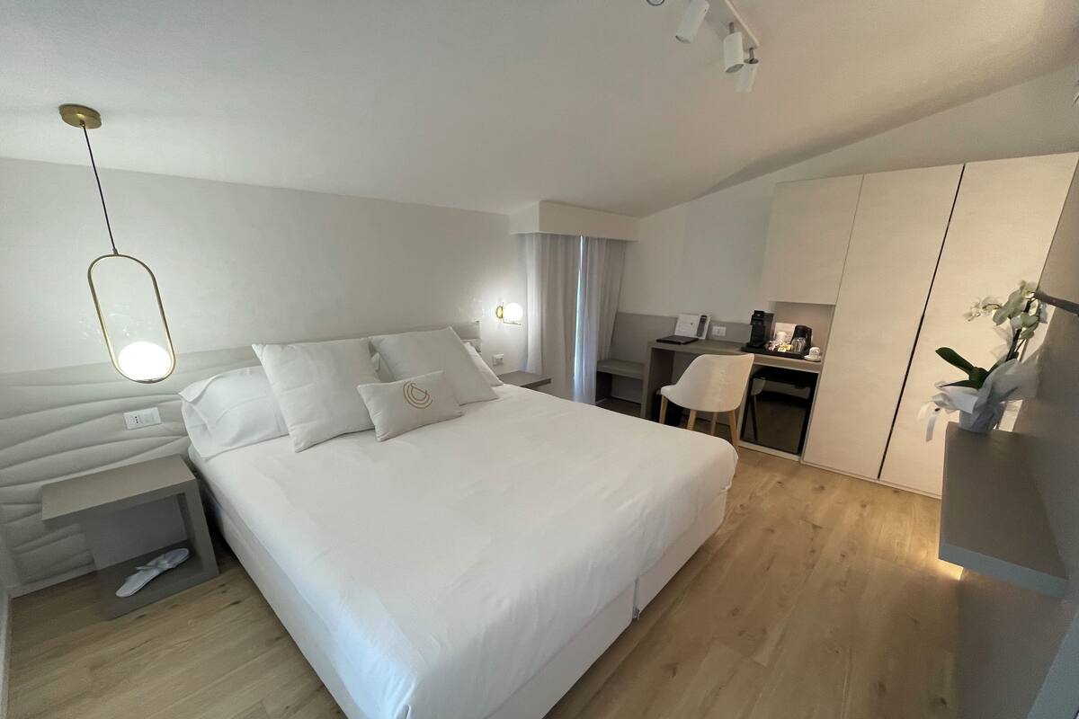 Een moderne hotelkamer met een groot bed, een bureau en een kledingkast.