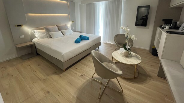 Une chambre d’hôtel moderne avec un grand lit, des tables de chevet, un bureau et une chaise.