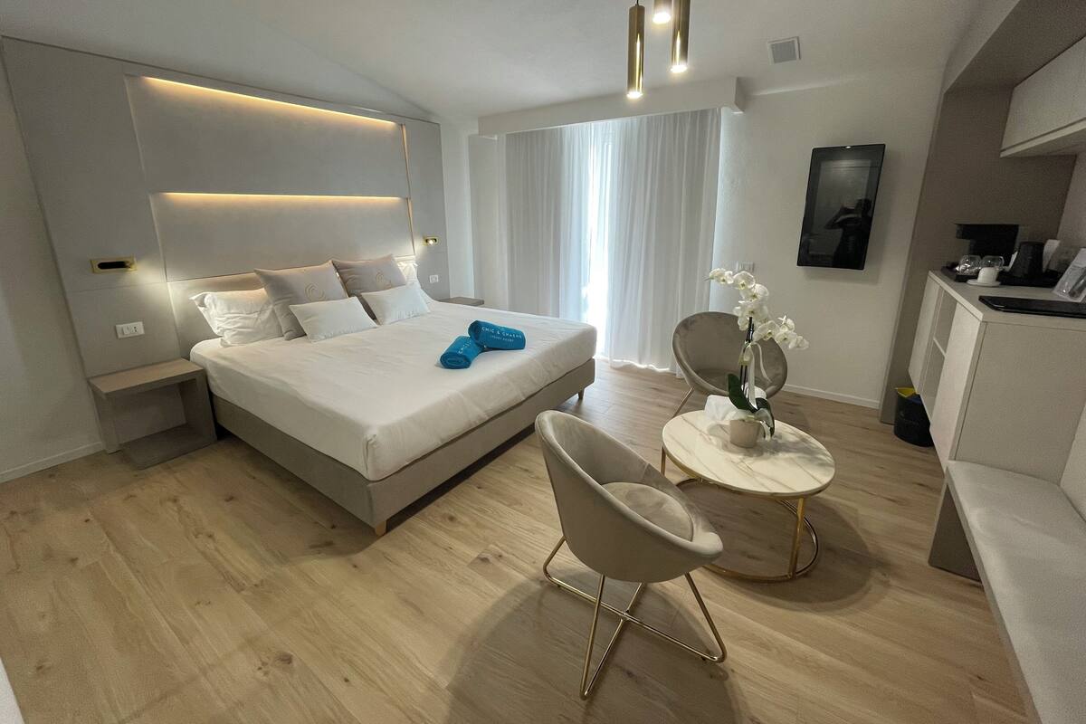 Een moderne hotelkamer met een groot bed, nachtkastjes, een bureau en een stoel.