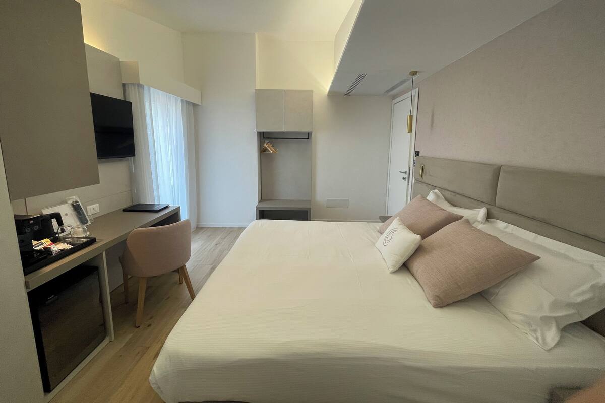 Een hotelkamer met een bed, een bureau, een stoel, een televisie en een kledingkast.