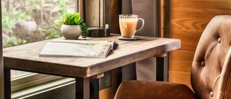 A cozy seating area with a leather chair, a table with a glass mug of coffee, a small potted plant, and a lamp.