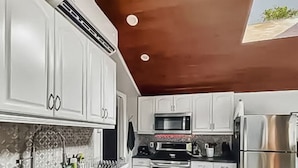 A modern kitchen with white cabinets, stainless steel appliances, and a wooden floor.