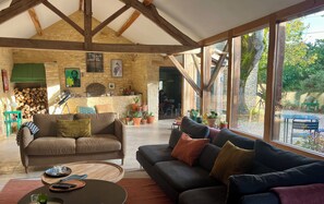 A spacious living area with a stone wall, wooden beams, and large windows.