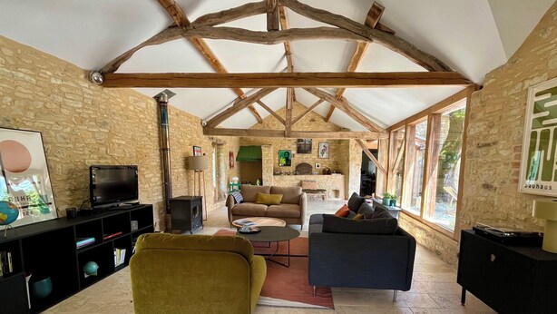 A spacious living area with stone walls, wooden beams, a television, sofas, and a fireplace. - Maison Nina: un Ancien Corps de Ferme Rénové Avec Piscine, Entre Dordogne et Lot (CAMPAGNAC LES QUERCY)