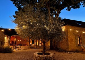 A stone building with a tree in the center, surrounded by a gravel courtyard.