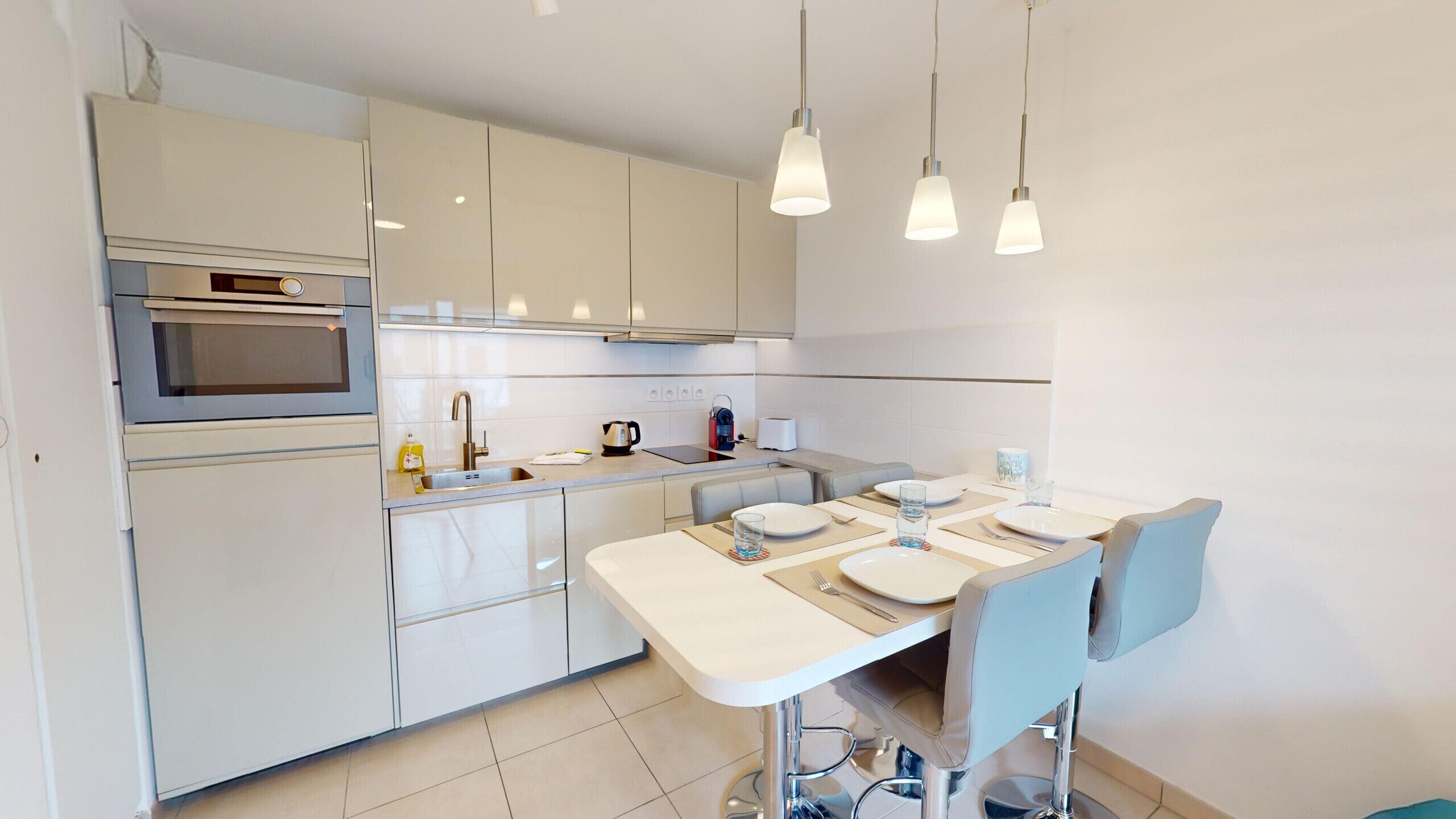 Une cuisine moderne avec un coin repas, des appareils en acier inoxydable et des luminaires suspendus.