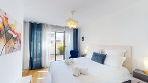 Ein Hotelzimmer mit Bett, Sessel, einem Gemälde und Blick durch die Tür.