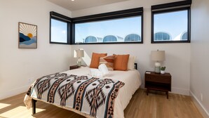 A bedroom with a large bed, two bedside tables, and three windows. - Rooftop Terrace Near Downtown Fort Worth (Fort Worth)