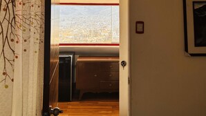 A room with a wooden floor, a small desk, a chair, and a window with a city view. - SUMMIT VIEWPOINT HOUSE (Cusco)