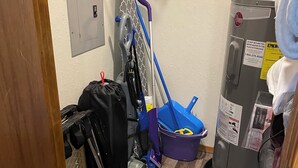 Una stanza di servizio con uno scaldabagno, uno straccio, un secchio e una borsa.