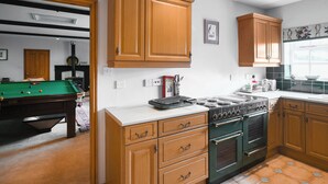 A kitchen with wooden cabinets, a stove, and a pool table in the adjacent room. - 2 bedroom accommodation in Quadford, near Bridgnorth (Quadford, near Bridgnorth)