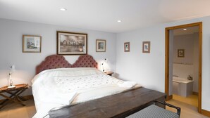 A bedroom with a large bed, a wooden bench, a nightstand, and framed pictures on the wall. - 2 bedroom accommodation in Quadford, near Bridgnorth (Quadford, near Bridgnorth)