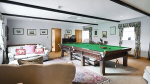 A room with a pool table, a sofa, a chair, and a door leading to another room. - 2 bedroom accommodation in Quadford, near Bridgnorth (Quadford, near Bridgnorth)