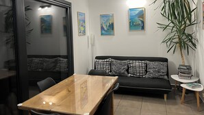 Un salon moderne avec un canapé noir, une table à manger en bois et une grande plante en pot.