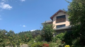 Une maison moderne avec un chemin de pierre menant à l’entrée, entourée d’une végétation luxuriante et de plantes en fleurs.