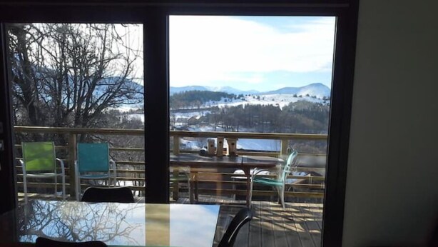 Un espace repas comprenant une table et des chaises, une cloison en verre et une vue sur un paysage enneigé grâce à de grandes fenêtres.