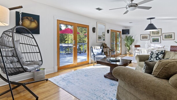 A spacious living room with a large window, a ceiling fan, and a comfortable seating area.