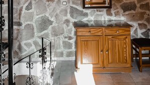 A room with a stone wall, wooden cabinet, and a chandelier. - Theonia Villas (Pefki)