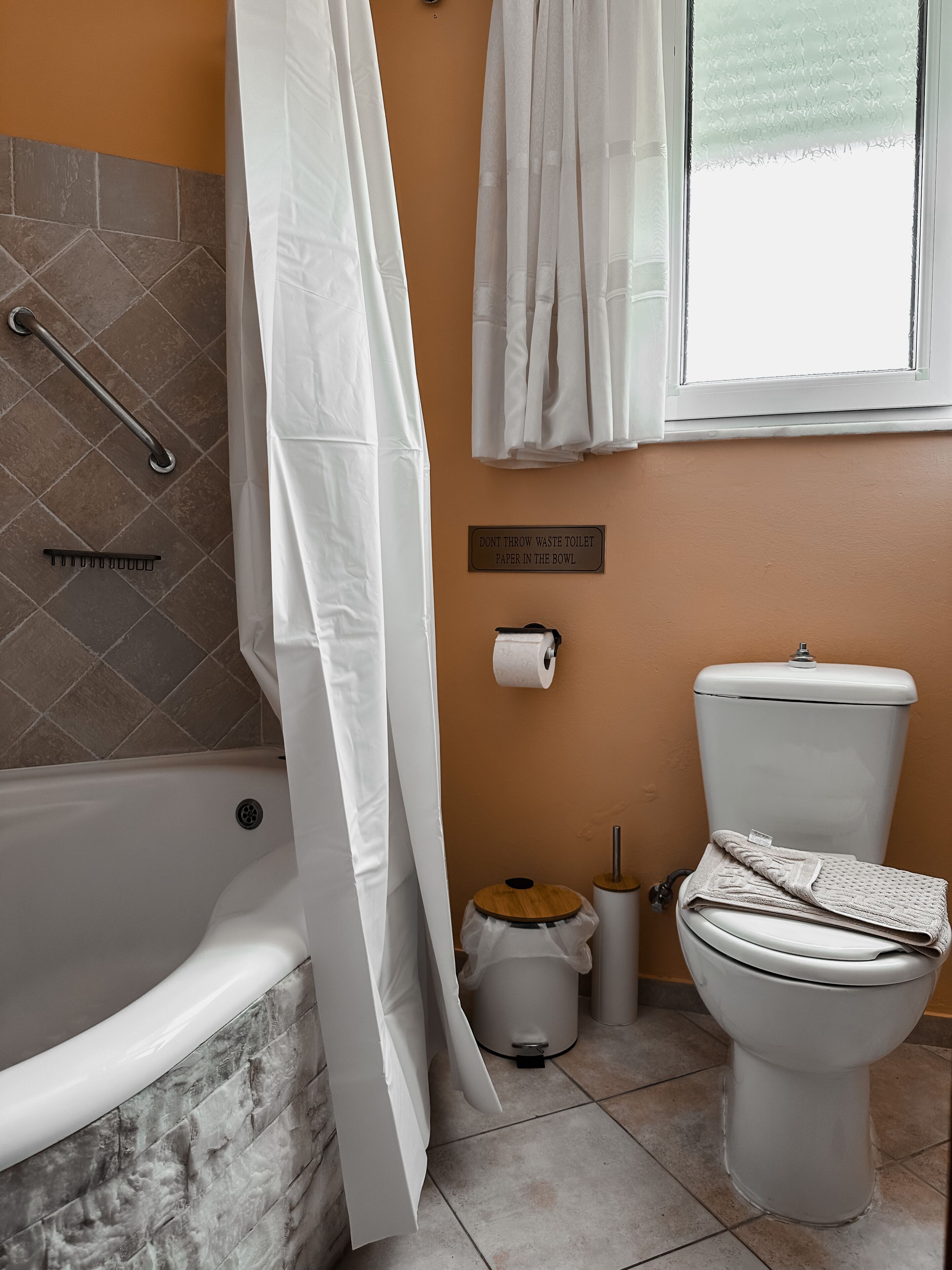 A bathroom with a bathtub, toilet, and a toilet paper holder.