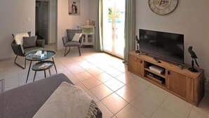 A modern living room with a large flat-screen TV, a sofa, a coffee table, and a TV stand with a decorative bird.