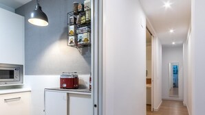A modern kitchen with white cabinets, a microwave, a toaster, and a hanging light fixture.