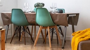 A dining area with a table set for four, including chairs, plates, glasses, and cutlery.