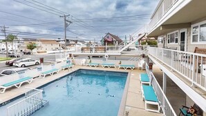 Une piscine avec des chaises longues et un escalier menant à un balcon.