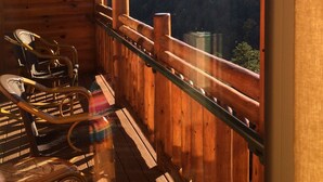 A wooden cabin with a balcony, wicker chairs, and a view of a forested mountain range. - Cabin, Prem unit w/ bal & jet tub. Sleeps 4. Avail. Wed 12/23/26 to Sun 12/27/26 (Gatlinburg)