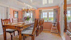 Un comedor con una mesa y sillas de madera, una araña y una ventana con cortinas.