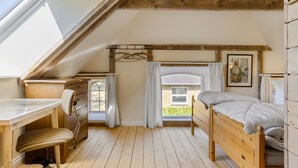 Un dormitorio acogedor en el ático con cama de madera, un escritorio y una silla.