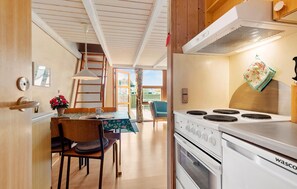 Une cuisine compacte équipée d’une cuisinière, d’un four et d’un coin repas avec une table et des chaises.
