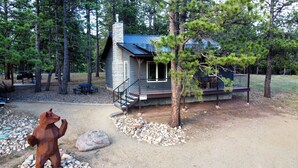 A cabin with a porch, a dining area, and a bear sculpture. - Incredible Cabin, Minutes to the Resort, King Bed, A/C, Fire pit (Angel Fire)