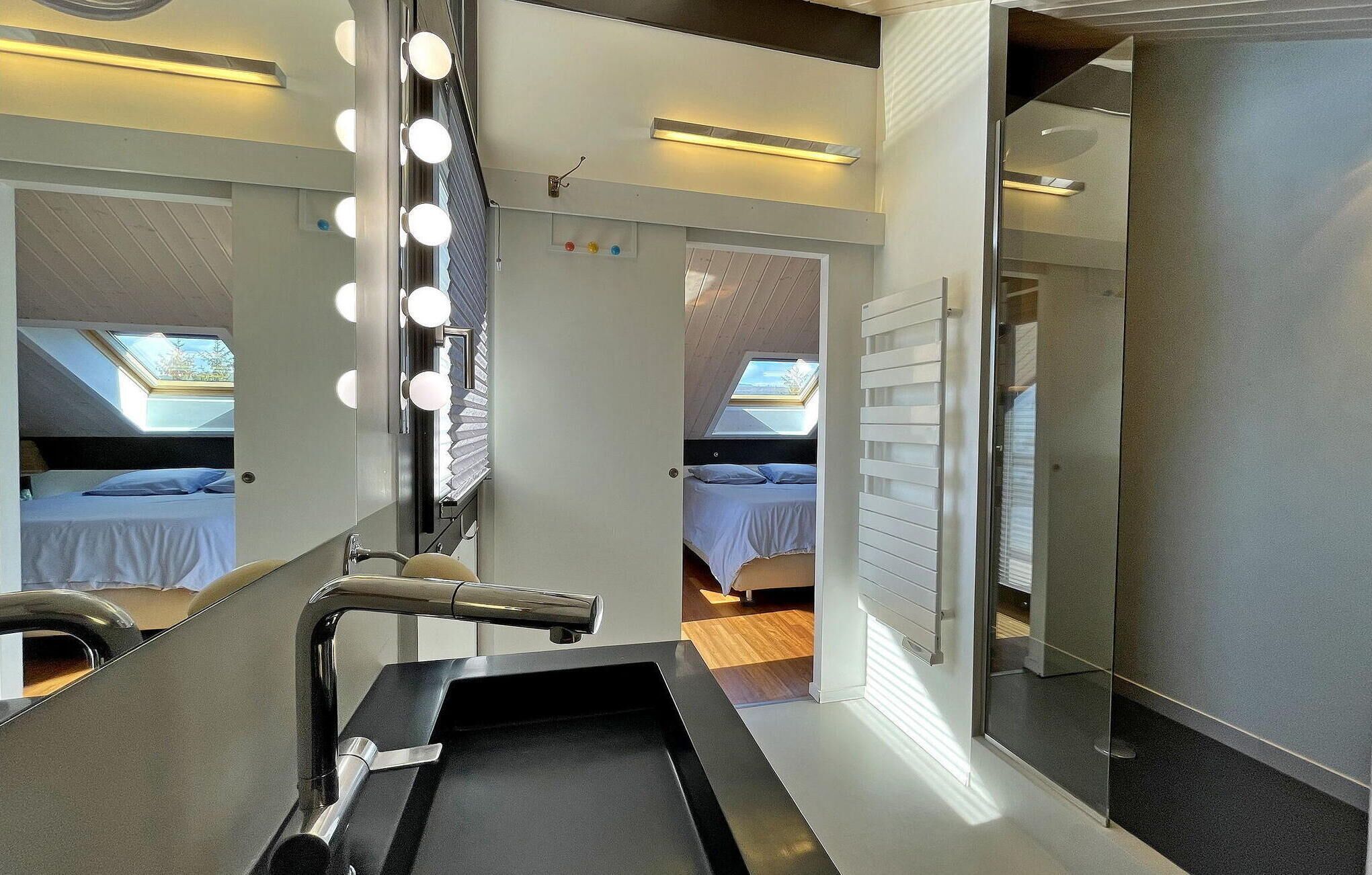Habitación de hotel compacta con tocador con espejo, una mesita de tocador pequeña y una cama con tragaluz.