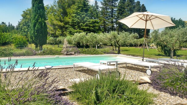 A pool area with lounge chairs and an umbrella, surrounded by greenery and trees. - Gorgeous home in Graveson with WiFi (Graveson)