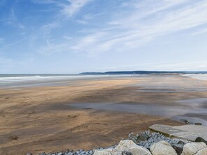 A beach with a rocky shoreline, waves, and a clear sky.