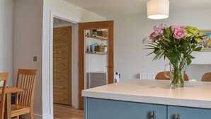 Et køkken med træskabe, en central ø, et spisebord med stole og en vase med blomster.
