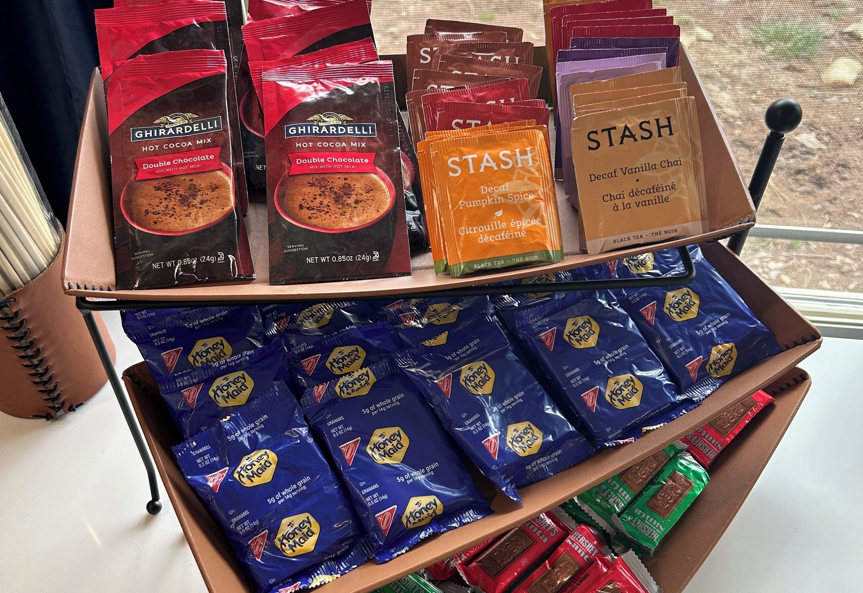 A display of various packaged food items, including hot cocoa mix, decaf vanilla chai, and honey maid tea bags.