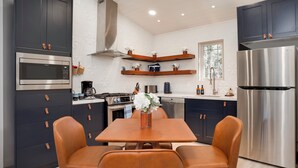 A modern kitchen with dark cabinets, stainless steel appliances, and a wooden dining table with chairs. - Spectacular Cabin in the Woods, Fire Pit, King Bed, Remodled, A/c (Angel Fire)