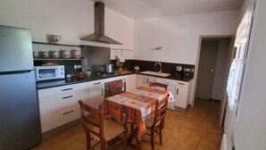 Cocina compacta con mesa, sillas, refrigerador, microondas, estufa y lavaplatos.