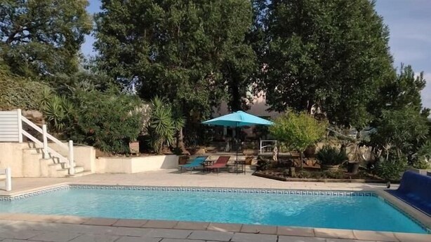 Una piscina con suelo de baldosas, una escalera y sillas de descanso.